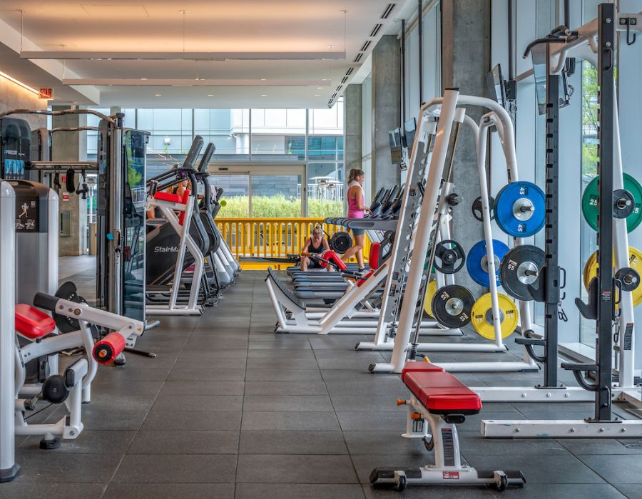 Optima Signature in Downtown Chicago with Modern gym with weight racks, benches, cardio machines, and people exercising by large windows.