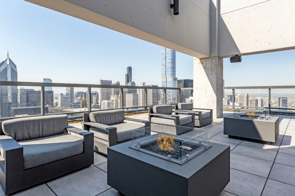 Optima Signature in Downtown Chicago with Modern Optima rooftop lounge with gray seating, fire tables, and city skyscrapers in the background creates an inviting outdoor space.