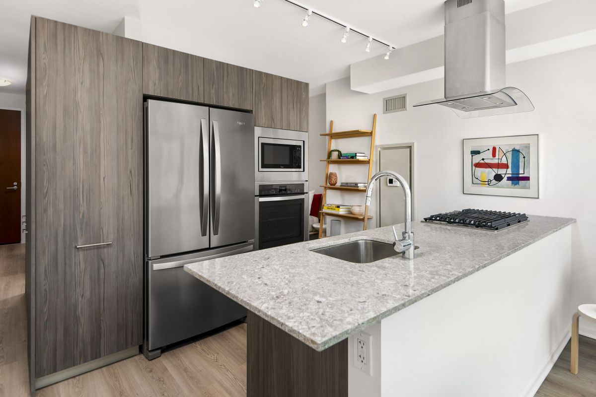 Optima Signature in Downtown Chicago with Modern kitchen with stainless steel appliances, wood cabinets, and a granite island—perfect for hosting at home.