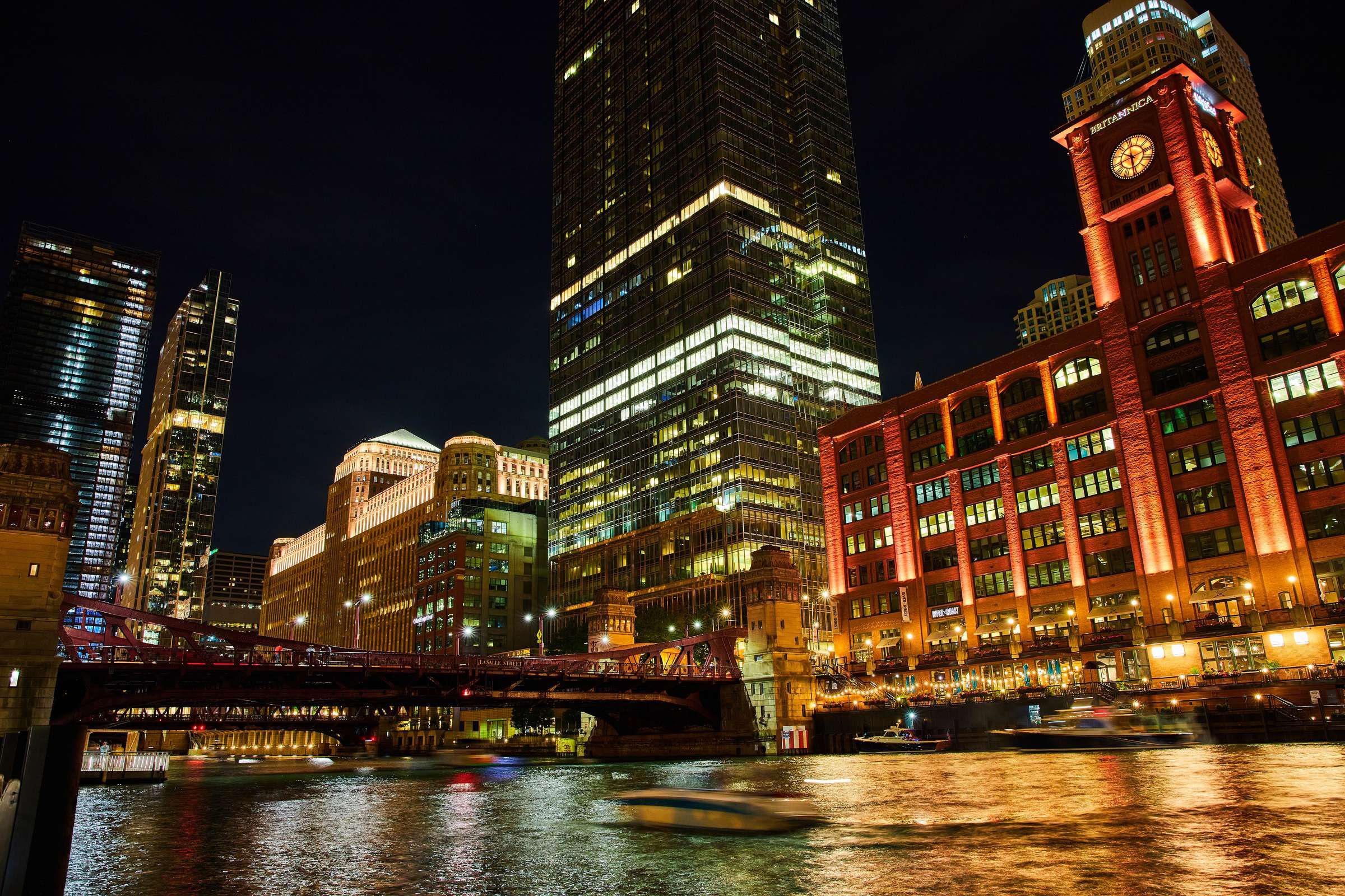 Optima Signature in Downtown Chicago with night view of illuminated skyscrapers and a bridge over the Chicago River in downtown Chicago.