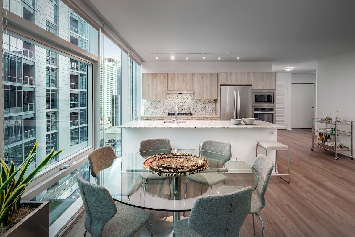 Optima Signature in Downtown Chicago with Modern kitchen and dining area with glass table, large windows, and city view.