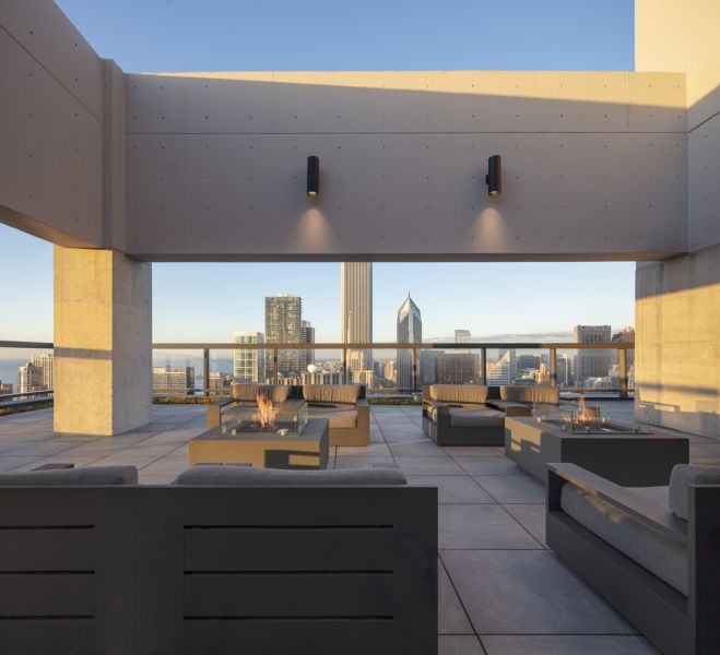 Optima Signature in Downtown Chicago with Modern rooftop lounge with fire pits, seating, and city skyline view at sunset.