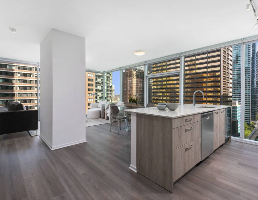 Optima Signature in Downtown Chicago with Modern open-plan apartment with large windows, city views, and a kitchen island in the foreground.