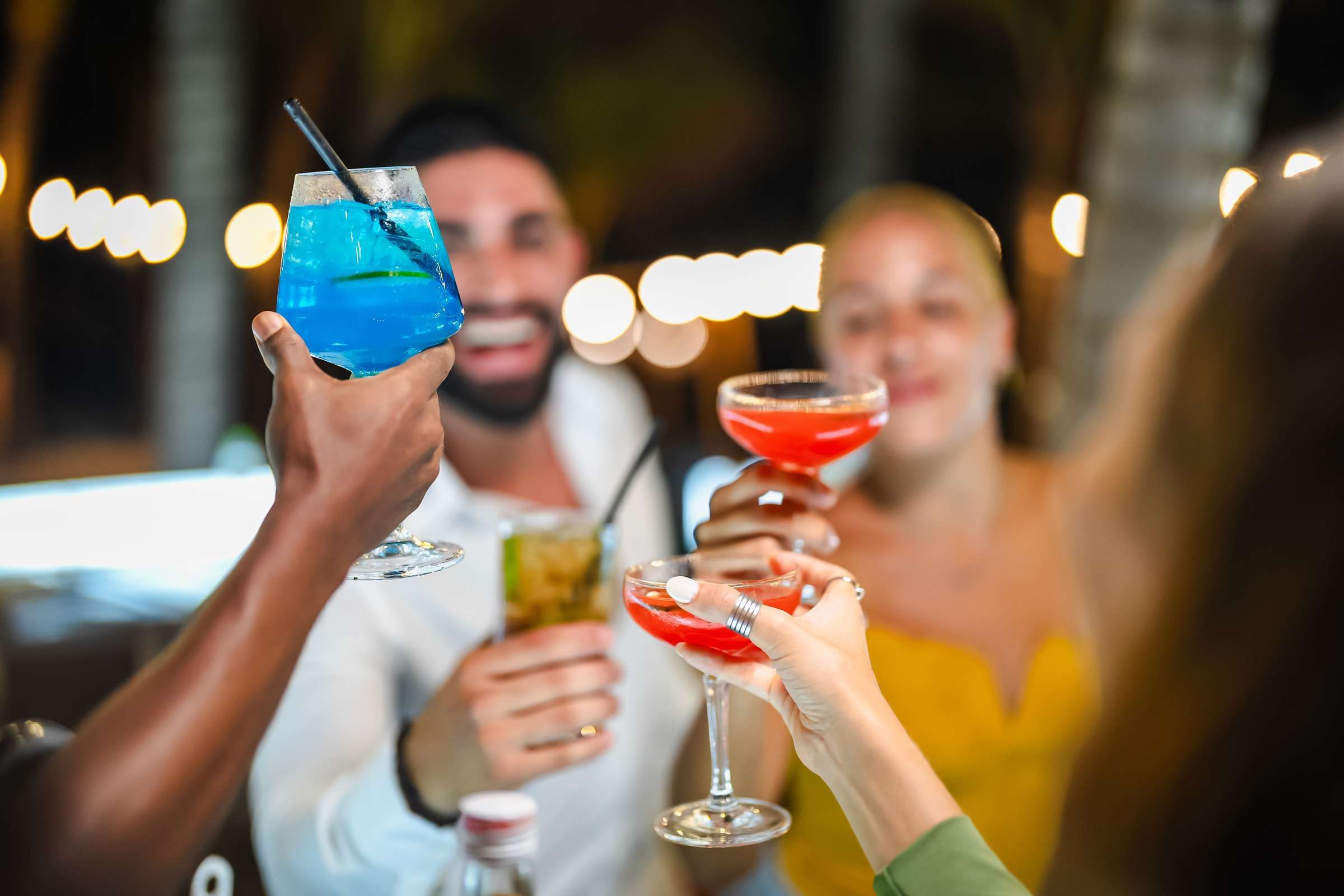 Optima Signature in Downtown Chicago with Four people clink colorful cocktails at night, celebrating together with blurred lights in the background.