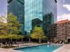 Optima Signature in Downtown Chicago with Rooftop outdoor pool with lounge chairs, surrounded by trees and city views at Optima Sky Decks on a sunny day.