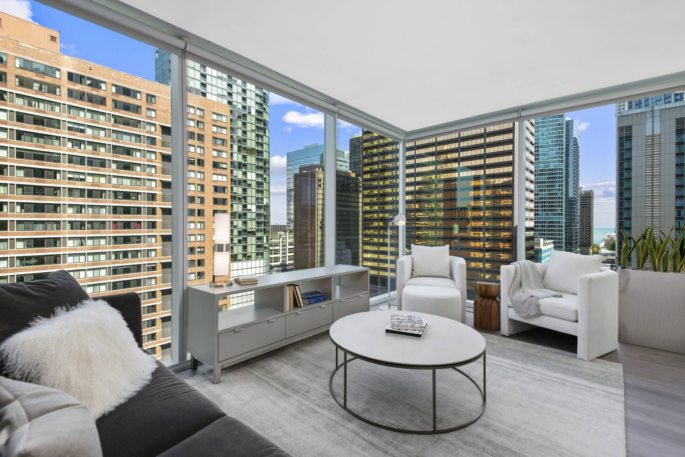 Optima Signature in Downtown Chicago with Modern high-rise living room with large windows, city views, cozy seating, and minimalist decor.