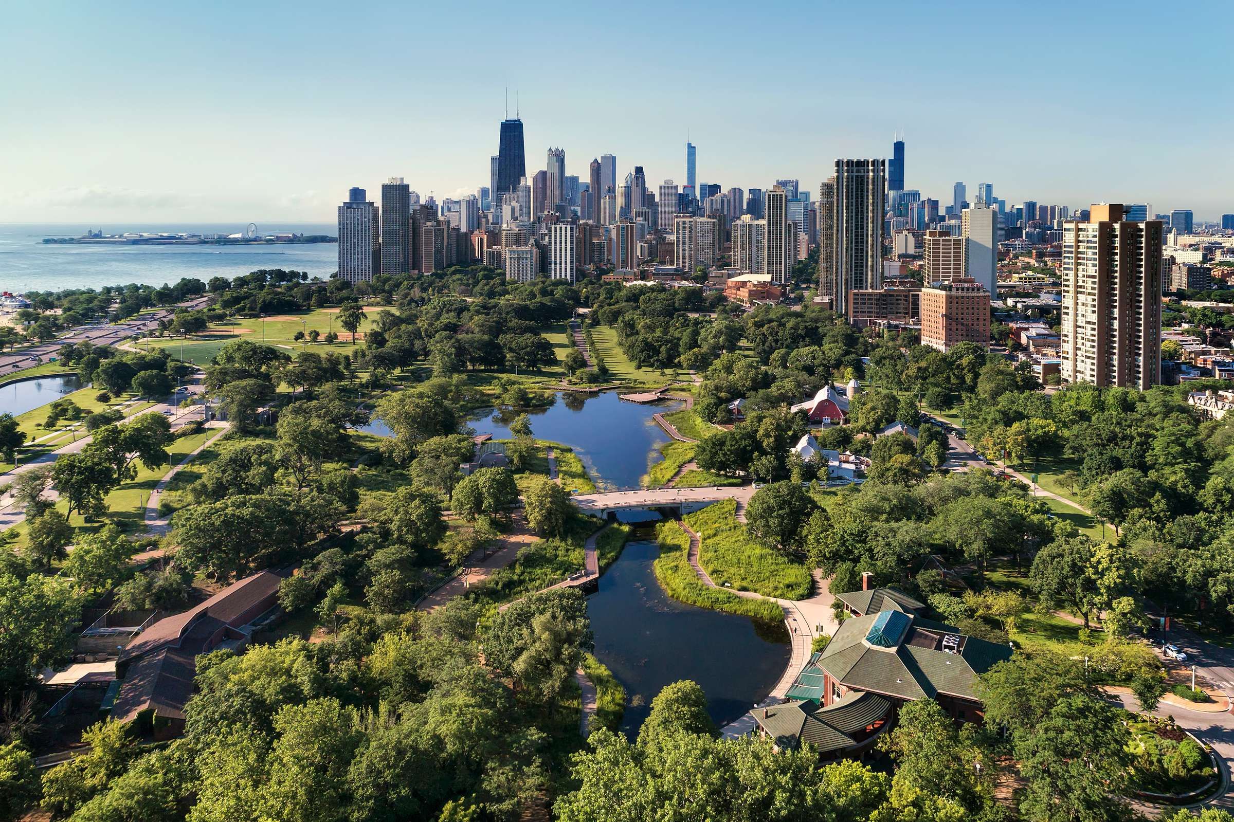 Optima Signature in Downtown Chicago with Aerial view of a city skyline with parks, trees, water, and tall buildings under a clear blue sky.