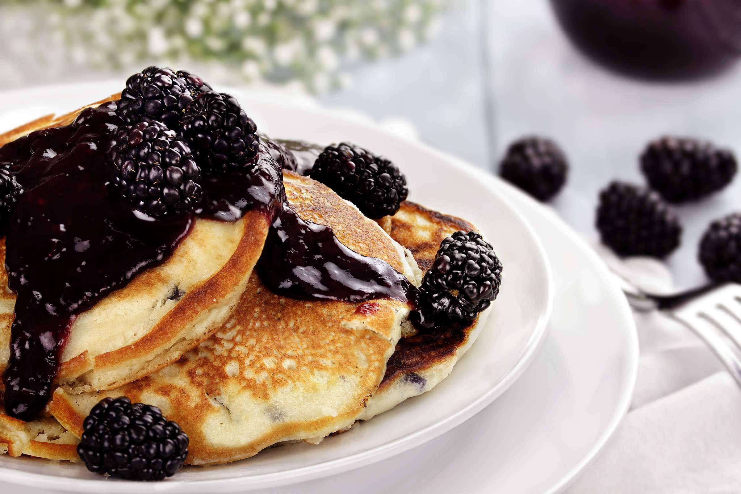 Optima Signature in Downtown Chicago with Stack of pancakes topped with blackberry sauce and fresh blackberries on a white plate.
