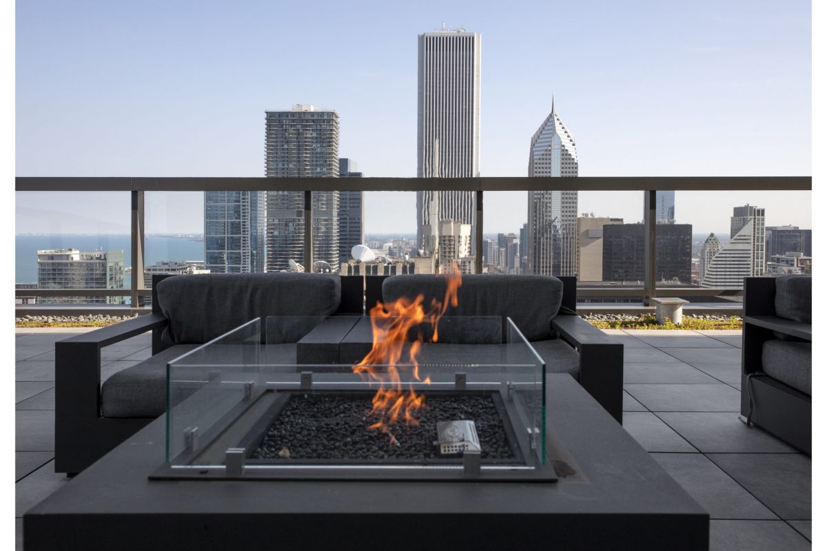 Optima Signature in Downtown Chicago with A rooftop patio at Optima Signature featuring a modern fire pit, lounge seating, and stunning city skyline views in the background.