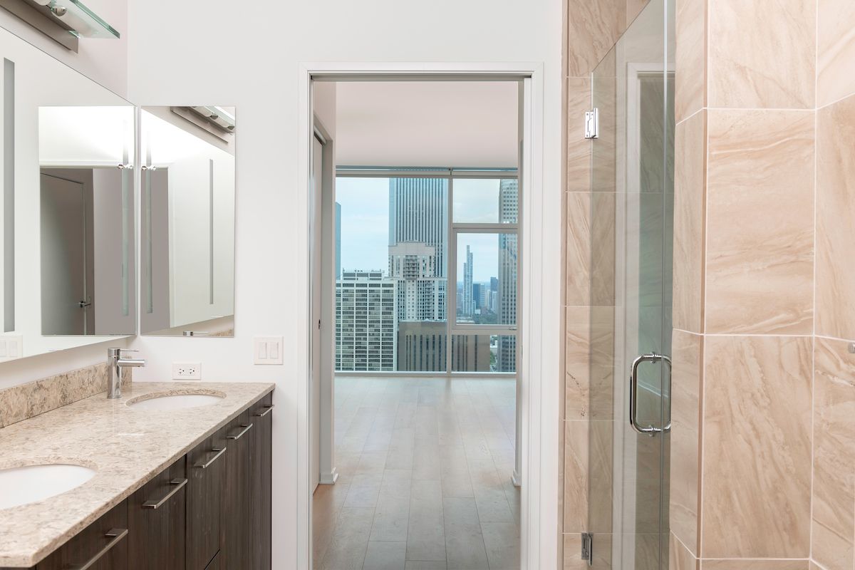 Optima Signature in Downtown Chicago with Modern bathroom design with marble counter, glass shower, and bright room featuring city views—perfect for inspired bathroom decor.