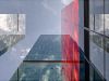 Optima Signature in Downtown Chicago with Tall glass skyscrapers from every angle, with Optima Signature’s red vertical section reflected in sky-filled windows above.