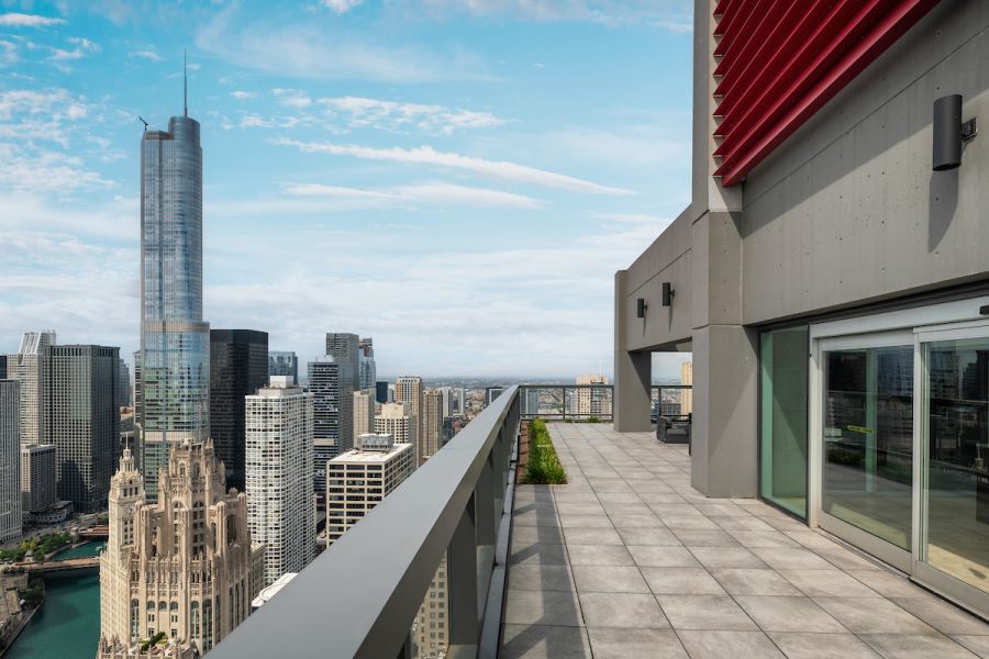 Optima Signature in Downtown Chicago with Rooftop terrace with city skyline view, including tall glass skyscrapers under a partly cloudy sky.