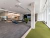 Optima Signature in Downtown Chicago with Modern office lounge with blue chairs, glass-walled meeting room, potted plants, and a virtual golf simulator for relaxation.