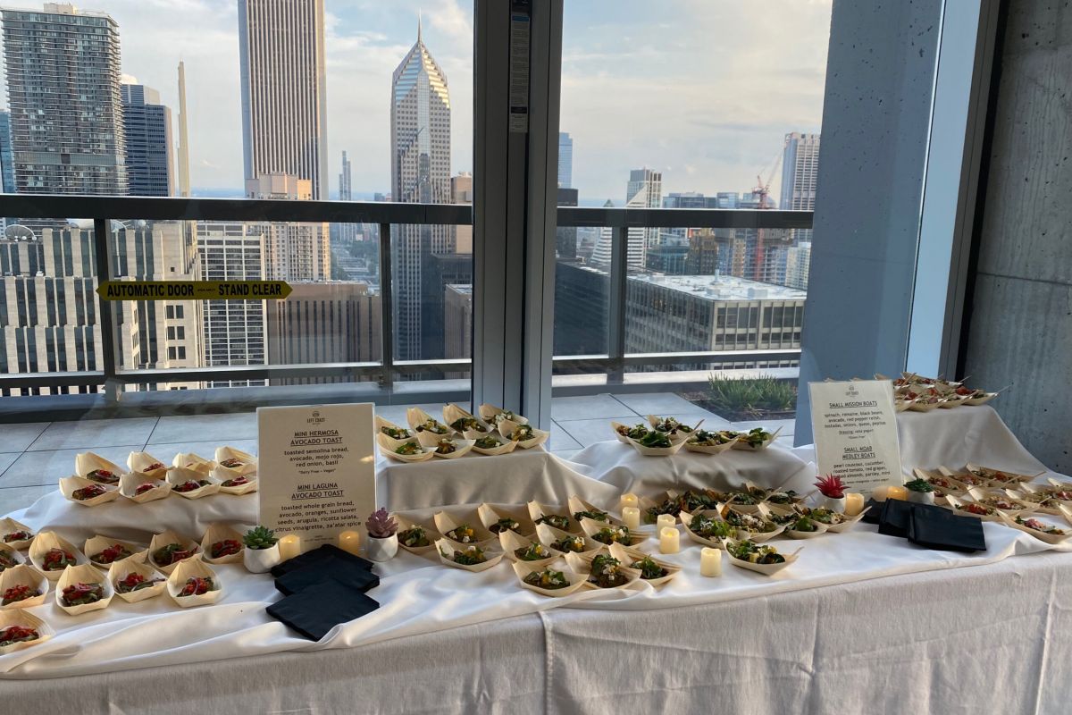 Optima Signature in Downtown Chicago with A table with many small food dishes is set up on a balcony at Optima Connect, offering perks like menus and candles above city skyscrapers.