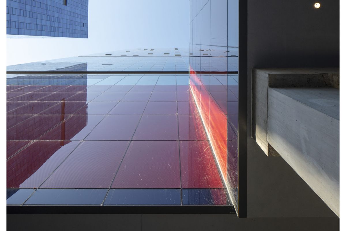 Optima Signature in Downtown Chicago with View from below of a modern glass building reflecting light, with a concrete structure on the right—where science meets architectural design.
