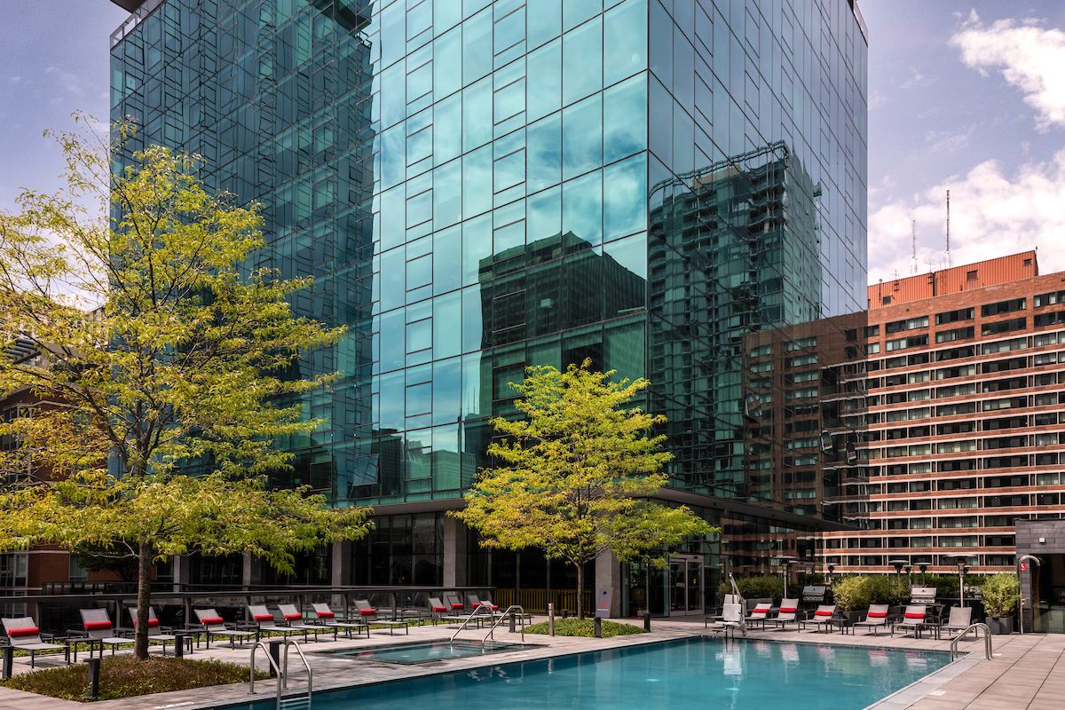 Optima Signature in Downtown Chicago with Rooftop outdoor pool with lounge chairs, surrounded by trees and city views at Optima Sky Decks on a sunny day.