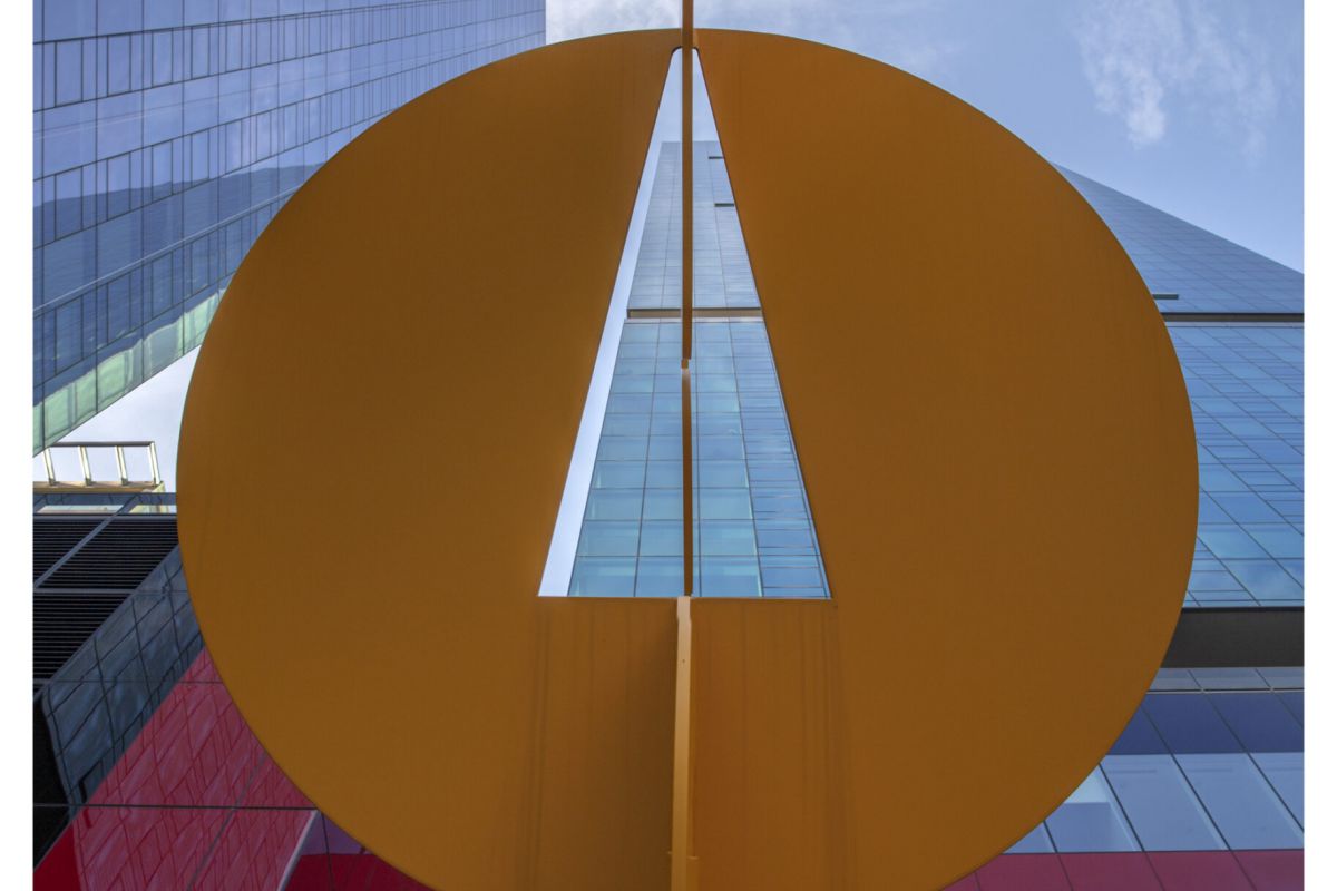 Optima Signature in Downtown Chicago with View looking up at modern buildings with a large yellow art sculpture in the foreground against a blue sky.