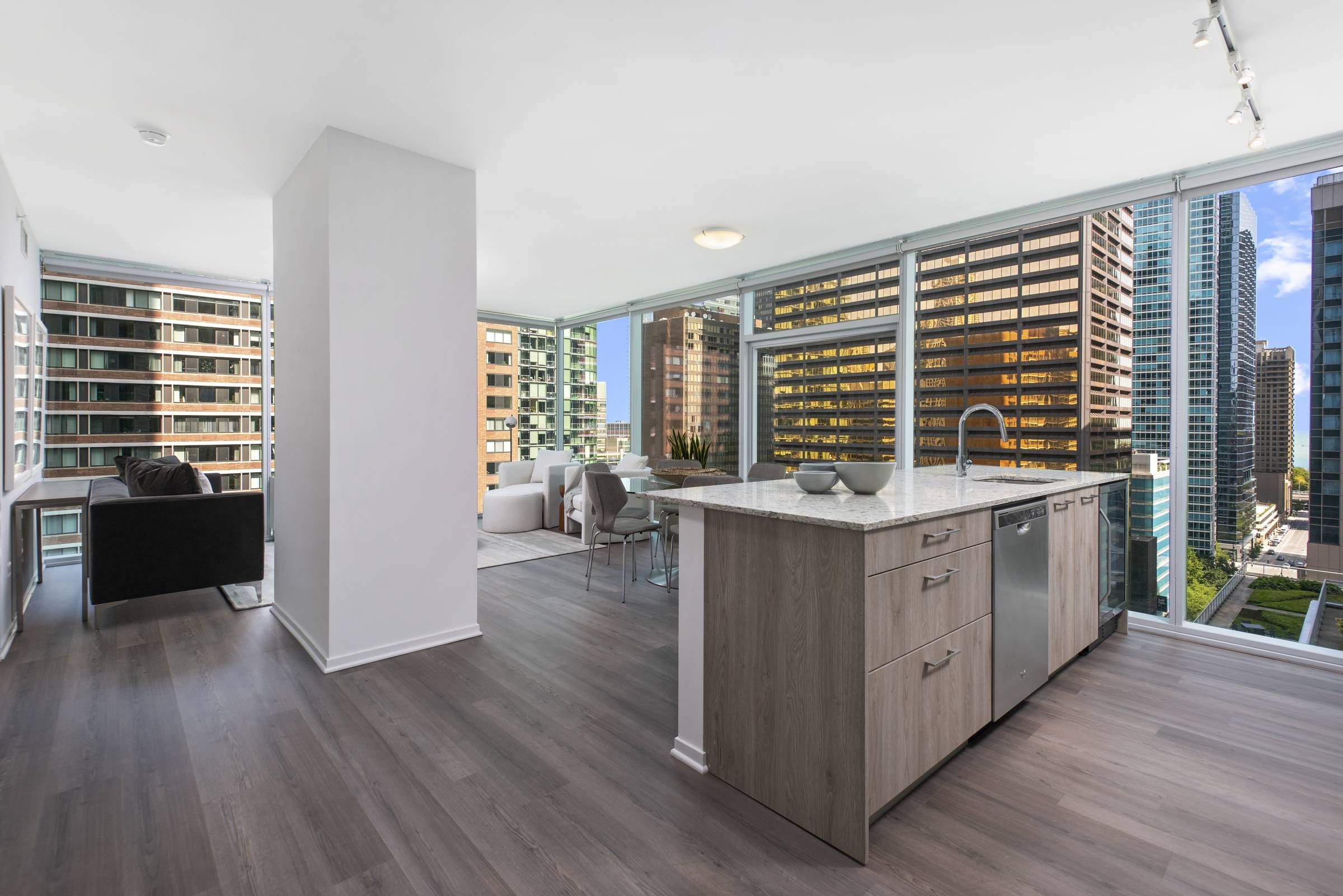 Optima Signature in Downtown Chicago with Modern open-plan apartment with large windows, city views, and a kitchen island in the foreground.