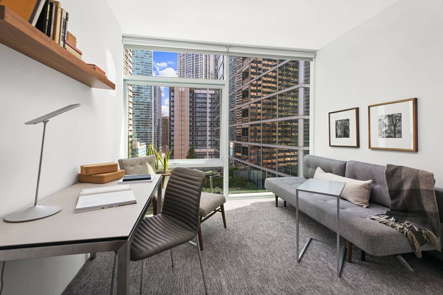 Optima Signature in Downtown Chicago with Modern home office with desk, chair, gray sofa, large window, and city skyscraper views.