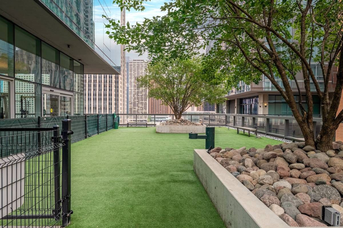 Optima Signature in Downtown Chicago with Rooftop terrace with artificial grass, trees, rocks, and city buildings in the background.