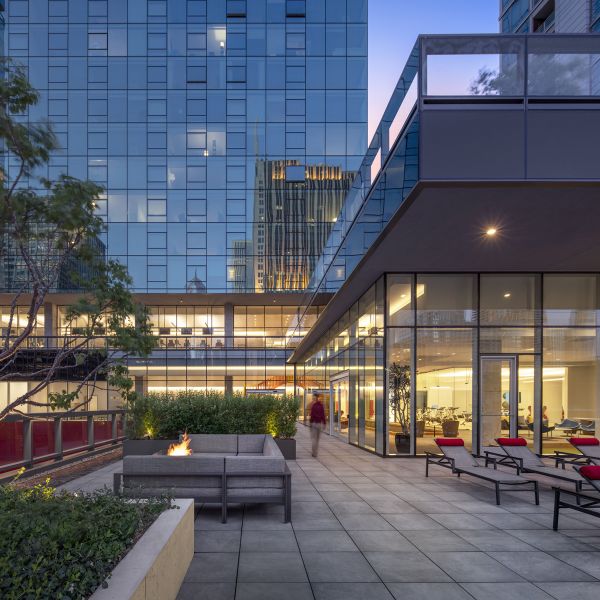 Optima Signature in Downtown Chicago with Modern city courtyard with lounge chairs, fire pit, and glass buildings at sunset.