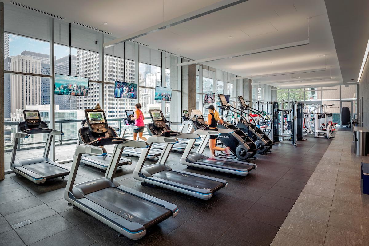 Optima Signature in Downtown Chicago with Modern gym with treadmills, large windows, and people embracing morning routines in a bright, productive space inside a city building.