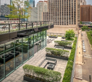 Optima Signature in Downtown Chicago with Modern rooftop terrace with seating, greenery, and glass walls, overlooking a city street and tall buildings.