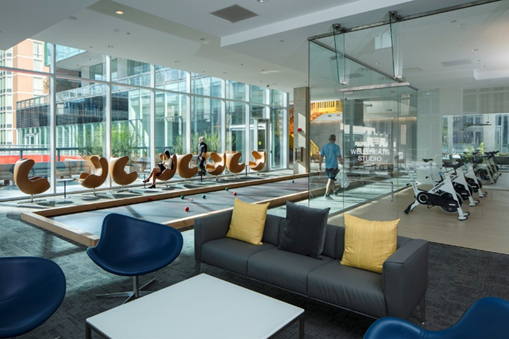 Optima Signature in Downtown Chicago with Modern lounge with stylish chairs, indoor bocce court, gym equipment, and large windows letting in natural light.