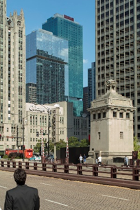 Optima Signature in Downtown Chicago with A man stands on a city bridge, facing tall skyscrapers under a clear blue sky.