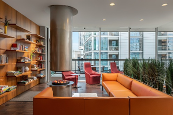 Optima Signature in Downtown Chicago with Modern lounge with orange sofas, bookshelf, fire pit, and city view—perfect for a home office inspired by Optima designs.