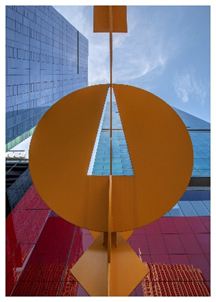 Optima Signature in Downtown Chicago with View of modern buildings and sky through a large abstract yellow sculpture with a triangular cutout.