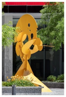 Optima Signature in Downtown Chicago with Yellow abstract metal sculpture stands outside a modern building, adding vibrant art to the community’s greenery and flowers.
