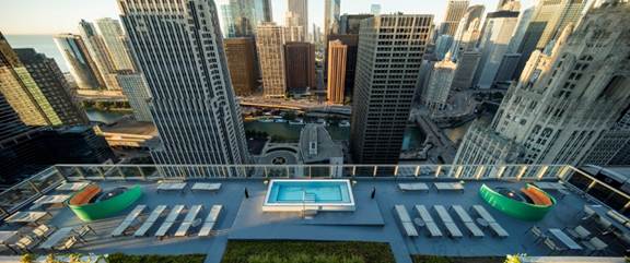 Optima Signature in Downtown Chicago with Rooftop pool and lounge area overlooking a city skyline with tall buildings and a river below.