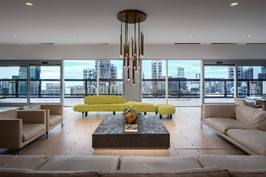 Optima Signature in Downtown Chicago with Modern living room at Optima Signature with beige sofas, green couch, coffee table, and large windows overlooking a cityscape.