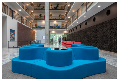 Optima Signature in Downtown Chicago with Modern lobby with blue curved seating, red couches, and multi-level balconies with plants and lights.