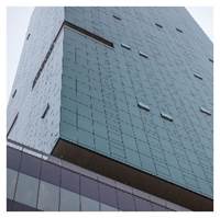 Optima Signature in Downtown Chicago with Tall modern glass building with small square windows, viewed from a low angle against a cloudy sky.