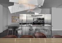 Optima Signature in Downtown Chicago with Modern kitchen with metal island, four stools, unique ceiling light, and abstract art on the wall.