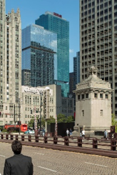Optima Signature in Downtown Chicago with Man standing on a city bridge with tall skyscrapers and historic buildings in the background.