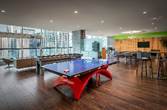 Optima Signature in Downtown Chicago with Modern office lounge with a ping pong table, sofas, and high tables—perfect inspiration for Hosting at Home, with large windows and wooden floors.