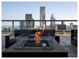 Optima Signature in Downtown Chicago with Modern rooftop patio with a glass fire pit, perfect for hosting at home against a stunning city skyline and tall buildings.