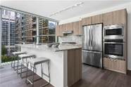 Optima Signature in Downtown Chicago with Modern kitchen with wood cabinets, stainless steel appliances, bar seating, and large windows overlooking city buildings.
