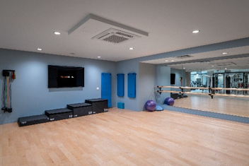 Optima Signature in Downtown Chicago with Empty fitness studio with exercise steps, resistance bands, stability balls, wall mirror, TV, and wooden floor.