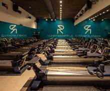 Optima Signature in Downtown Chicago with A modern gym studio with rows of rowing machines facing mirrored walls and teal walls with white logo graphics.