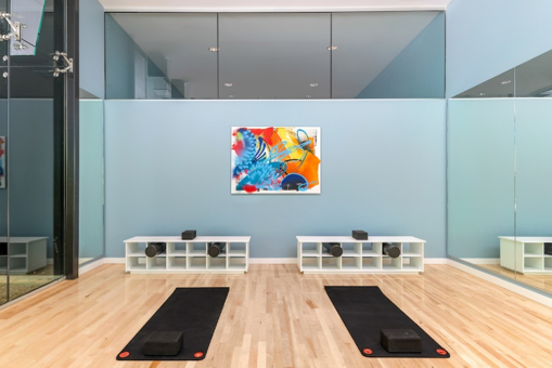 Optima Signature in Downtown Chicago with Two black yoga mats with blocks on a light wood floor in a bright, modern exercise room with blue walls and abstract art.