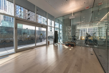 Optima Signature in Downtown Chicago with Empty modern gym room with wooden floor, large windows, glass walls, and exercise bikes in a separate area.